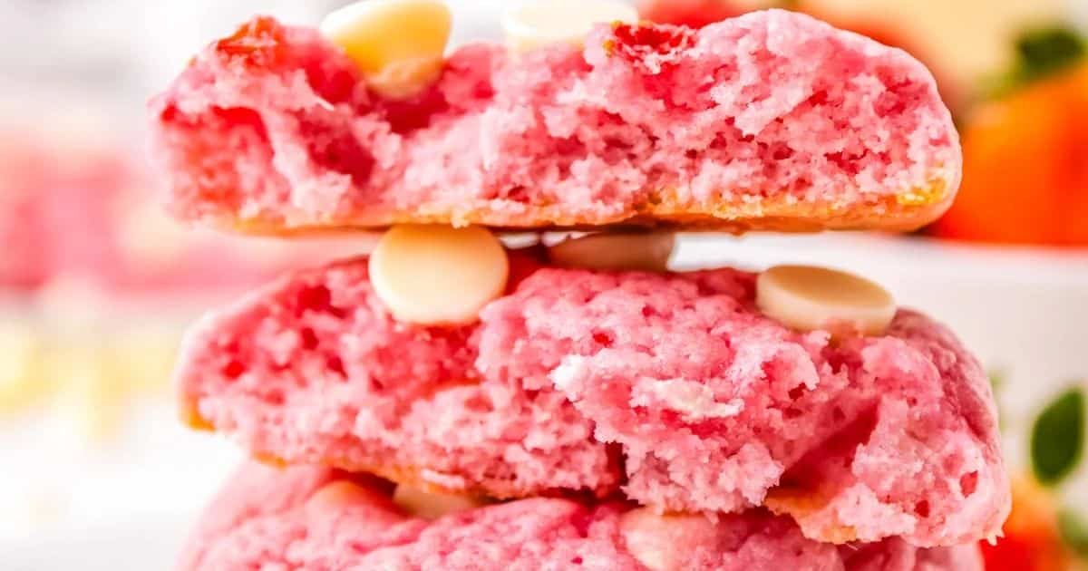 Close-up of pink cookies with white chocolate chips, stacked and broken open to show a soft, crumbly texture.