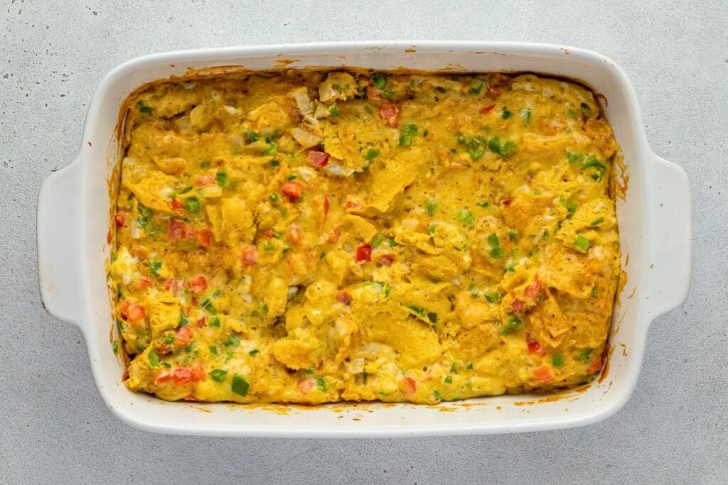 Baked Migas casserole with eggs and diced vegetables in a white rectangular baking dish.