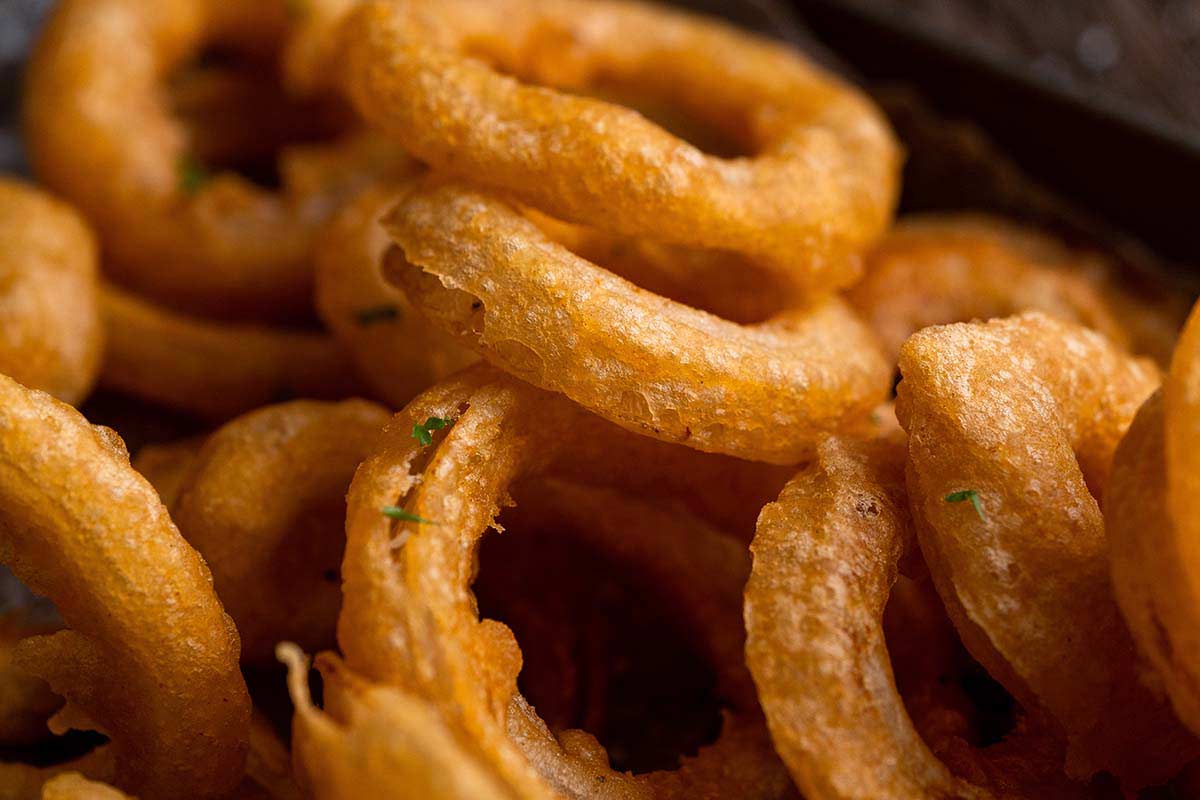 Close-up of golden, crispy fried onion rings stacked together.