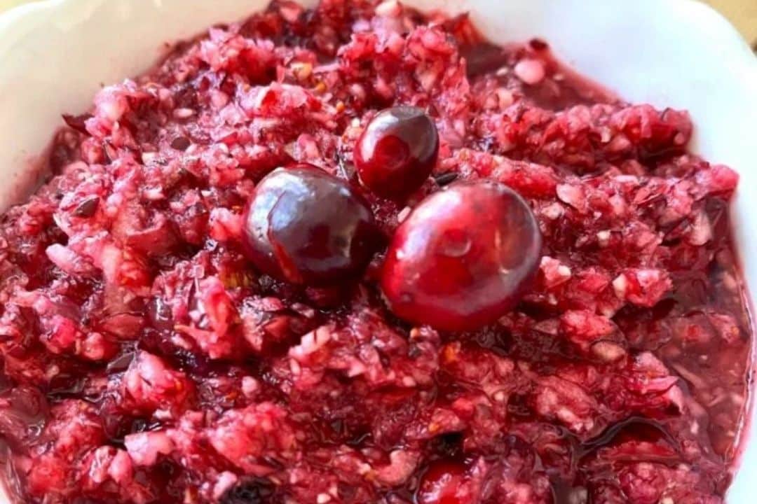 Chopped cranberry relish topped with whole cranberries in a white bowl.