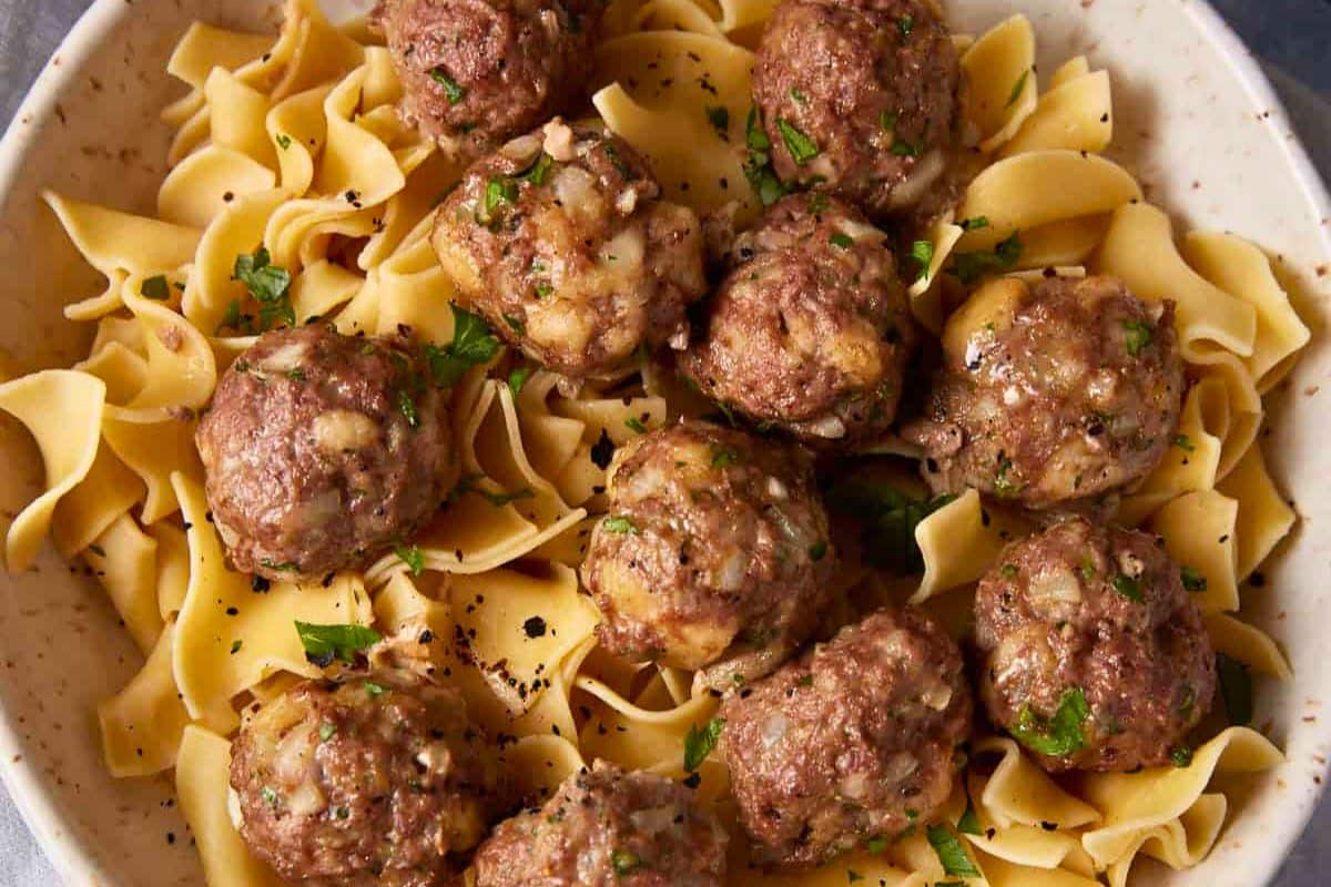 A close up shot of baked meatballs and gravy.