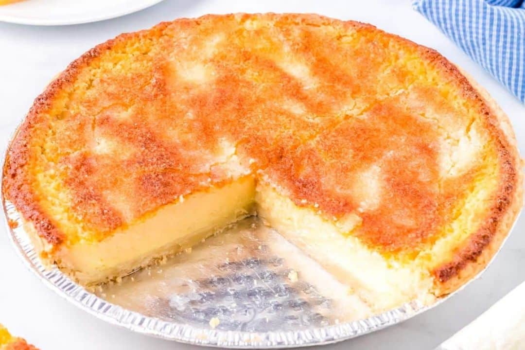 A golden brown chess pie in a foil pan with one slice removed.
