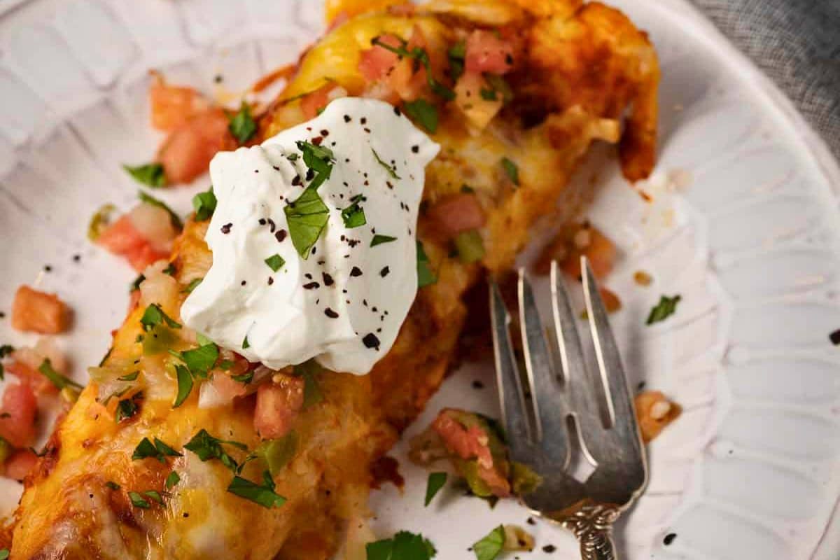 A close up shot of cheese and chicken enchiladas.
