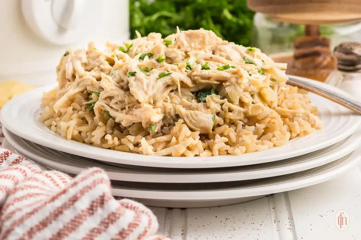 Shredded chicken served over a bed of brown rice on a white plate.