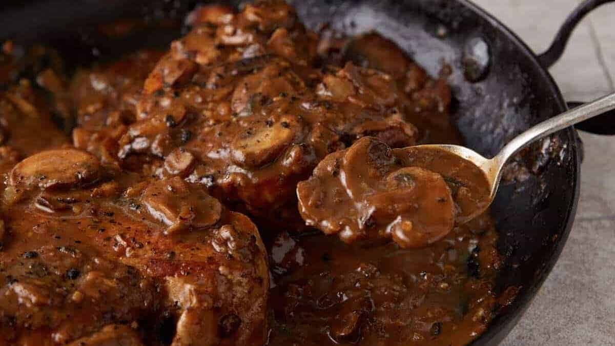 A close up shot of pork chops with mushroom gravy.