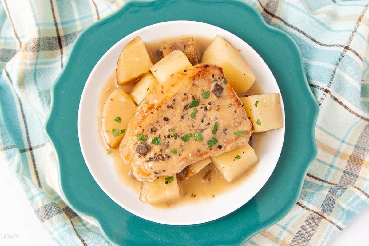 A close up shot of pork chops with potatoes.