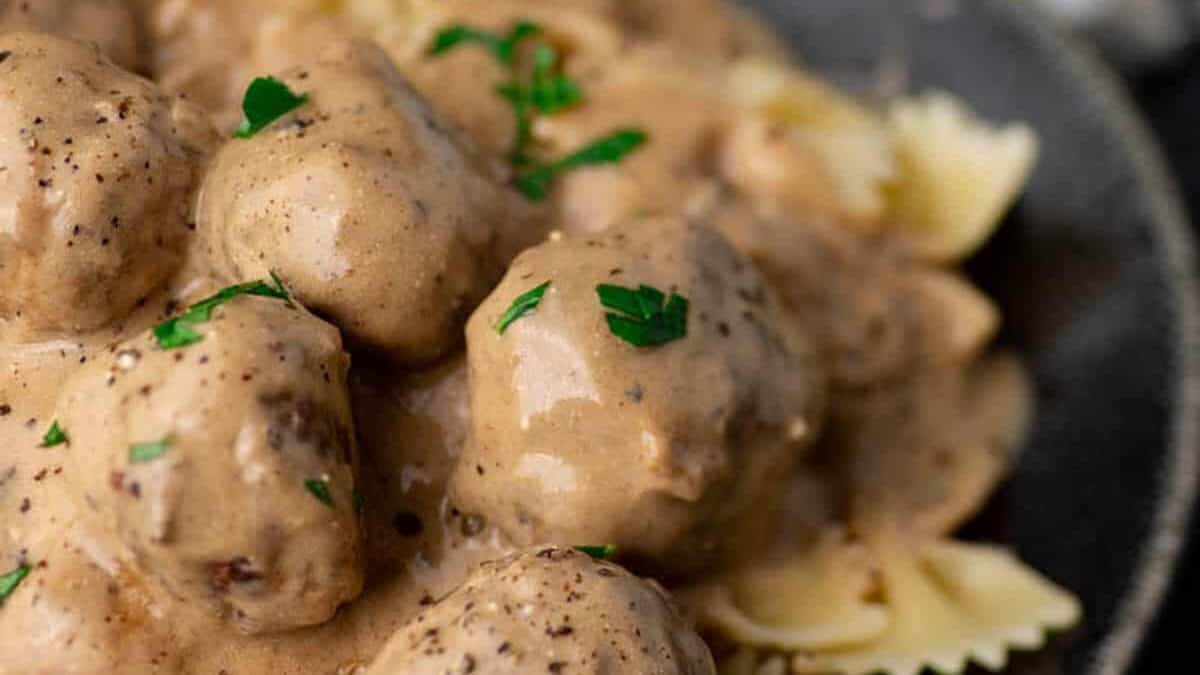 Meatballs in a creamy gravy served over bow tie pasta and garnished with parsley.
