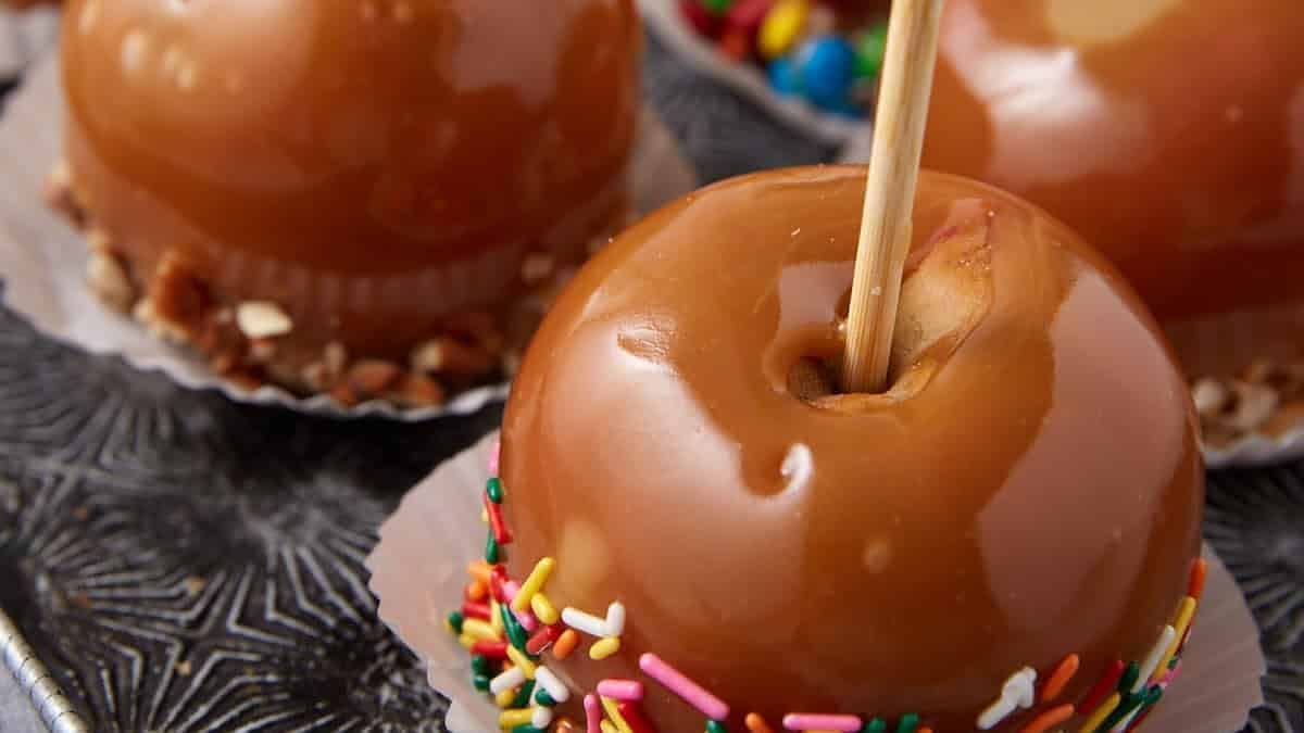 Caramel apples with colorful sprinkles on sticks.