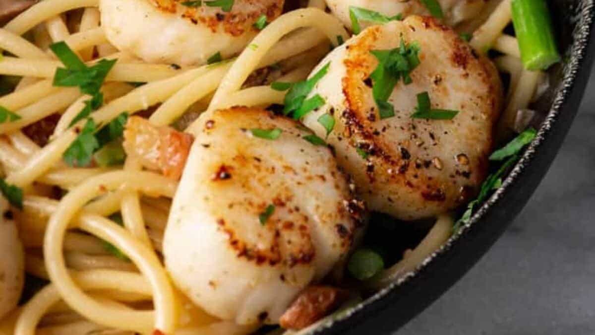 Seared scallops served over pasta with herbs.