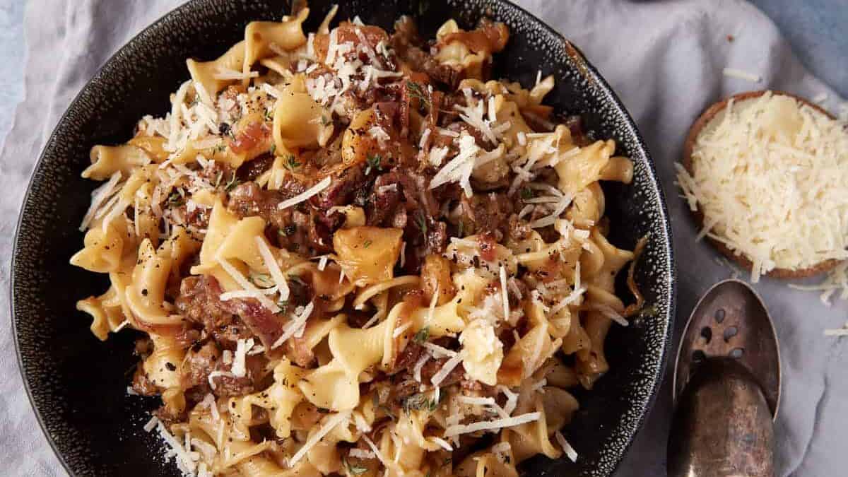 A close up shot of pasta with sausage and onions.
