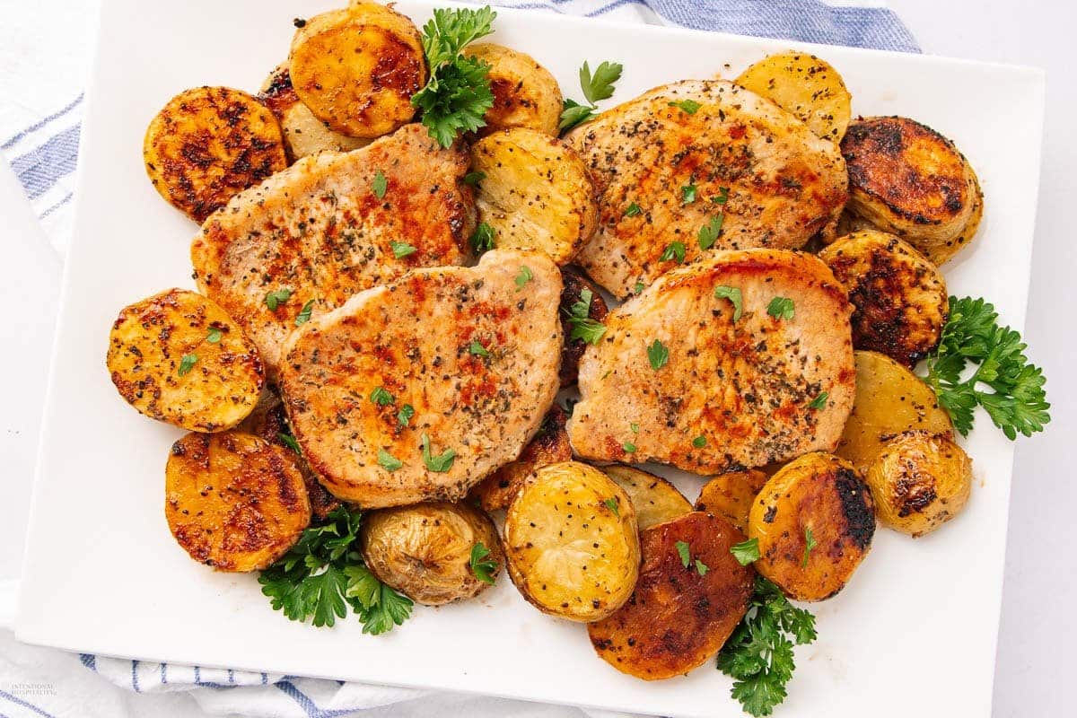 A close up shot of oven pork chops with potatoes.
